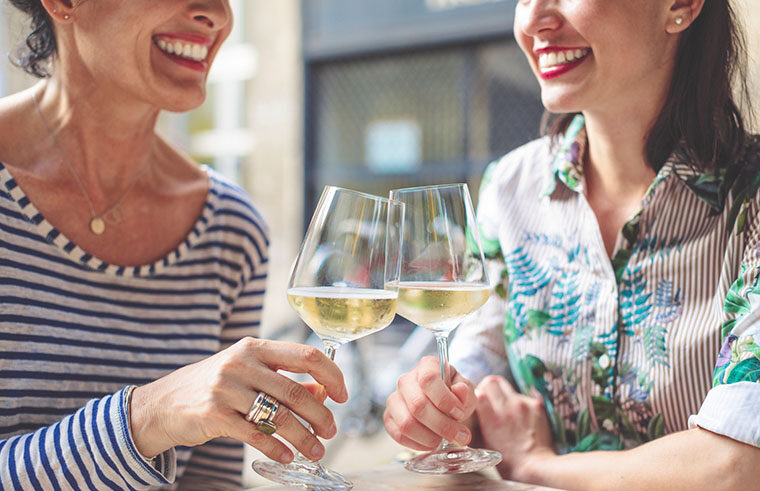 Two women smiling and clinking glasses of wine - feature