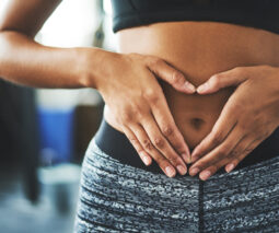 A woman holds her hands over her flat belly